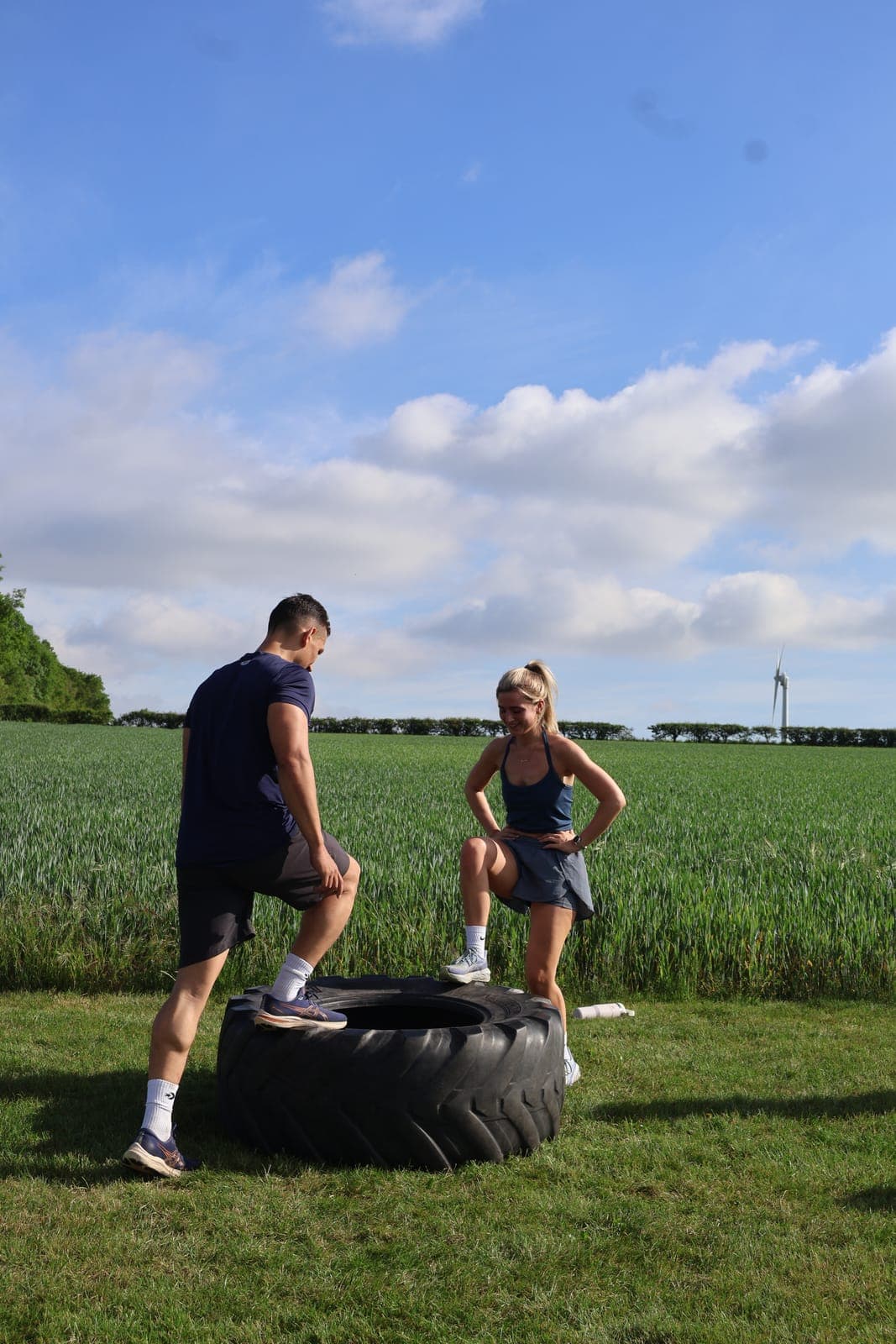 Two Fit Farm members stepping up onto a tractor tyre in the field